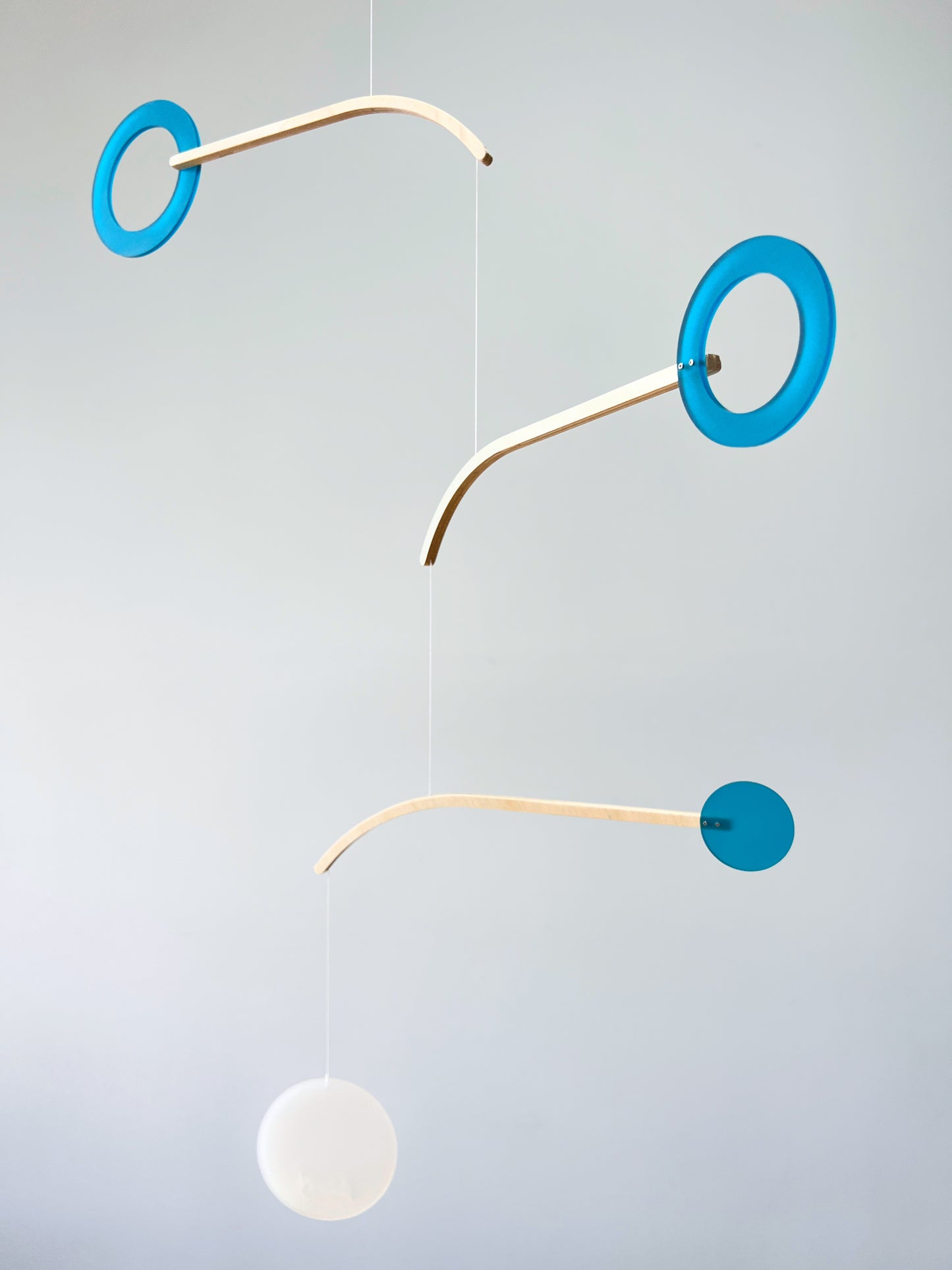 Teal Kinetic Hanging Mobile Sculpture, Minimalistic Circles Adult Mobile Home Decor - Halo Halo Handcrafted By The Illuminist

Introducing Halo Halo Mobile - A stunning piece of kinetic art that will bring movement and interest to any room. Handcrafted from responsibly sourced engineered birch, this unique mobile features six halo rings of increasing width and size in frosted Orange acrylic. Similar to my original Halo mobile but on a verticle plane. 
