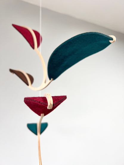 Felt & Wood Leaf Mobile, Adult or Baby Mobile Gift Idea, Plant inspired Sculpture, Kinetic Art Mobile. Maroon, Teal and Brown. 

This vibrant felt leaf mobile is a charming addition to your home decor, offering a lightweight and artistic touch. Handmade with colorful felt leaf shapes, it features independently rotating wooden stems crafted from birch wood, arranged in a customizable color order that can be adjusted anytime.