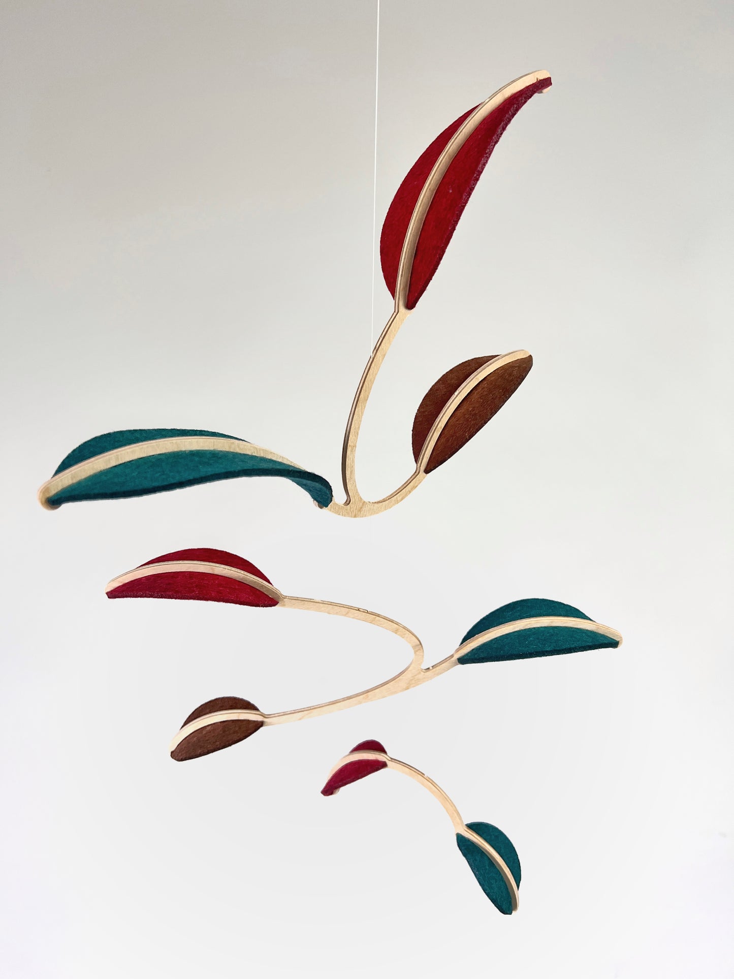 Felt & Wood Leaf Mobile, Adult or Baby Mobile Gift Idea, Plant inspired Sculpture, Kinetic Art Mobile. Maroon, Teal and Brown. 

This vibrant felt leaf mobile is a charming addition to your home decor, offering a lightweight and artistic touch. Handmade with colorful felt leaf shapes, it features independently rotating wooden stems crafted from birch wood, arranged in a customizable color order that can be adjusted anytime.