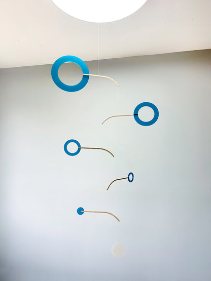 Teal Kinetic Hanging Mobile Sculpture, Minimalistic Circles Adult Mobile Home Decor - Halo Halo Handcrafted By The Illuminist

Introducing Halo Halo Mobile - A stunning piece of kinetic art that will bring movement and interest to any room. Handcrafted from responsibly sourced engineered birch, this unique mobile features six halo rings of increasing width and size in frosted Orange acrylic. Similar to my original Halo mobile but on a verticle plane. 
