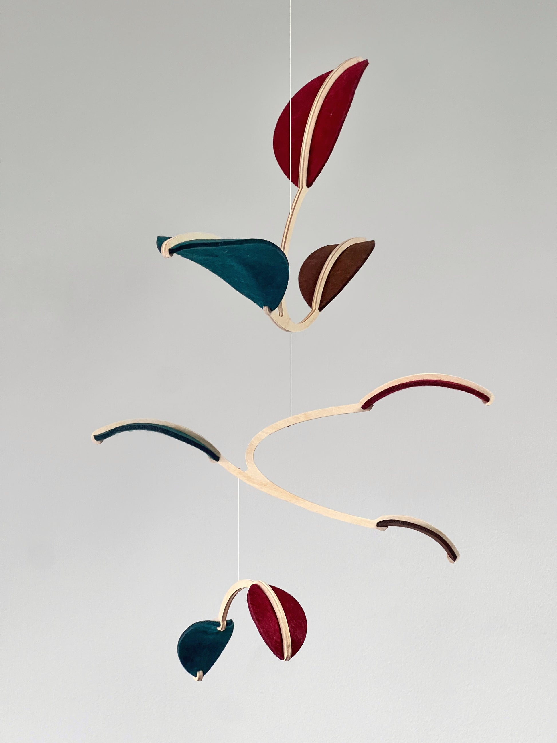 Felt & Wood Leaf Mobile, Adult or Baby Mobile Gift Idea, Plant inspired Sculpture, Kinetic Art Mobile. Maroon, Teal and Brown. 

This vibrant felt leaf mobile is a charming addition to your home decor, offering a lightweight and artistic touch. Handmade with colorful felt leaf shapes, it features independently rotating wooden stems crafted from birch wood, arranged in a customizable color order that can be adjusted anytime.