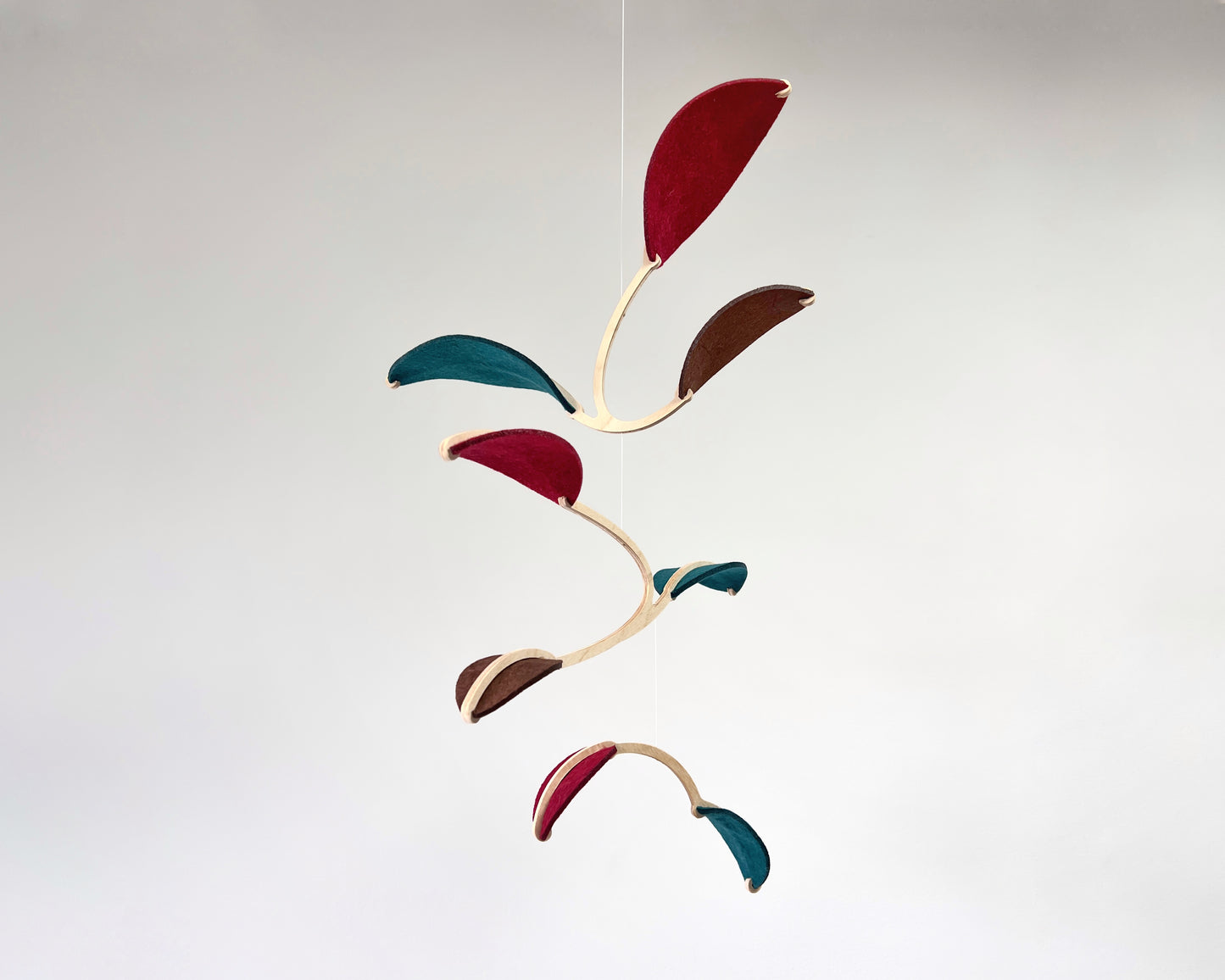 Felt & Wood Leaf Mobile, Adult or Baby Mobile Gift Idea, Plant inspired Sculpture, Kinetic Art Mobile. Maroon, Teal and Brown. 

This vibrant felt leaf mobile is a charming addition to your home decor, offering a lightweight and artistic touch. Handmade with colorful felt leaf shapes, it features independently rotating wooden stems crafted from birch wood, arranged in a customizable color order that can be adjusted anytime.