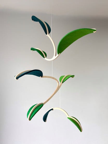 Wall Hanging Plant Mobile, Kinetic Artificial Plant Wall Art for Planted living Space, Leafy Office & Nature Nursery decor. Alternative Gift

Felt Leaf Mobile can be used as a ceiling hanging mobile or as a wall hanging plant mobile. 

Elevate your space with this versatile Midcentury Modern Mobile, designed for both nurseries and adult living areas. Crafted from natural wood with deep teal and green shades of soft felt, this handmade nursery mobile embodies a minimalist and Scandinavian aesthetic.