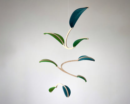 Felt Leaf Mobile 

   Elevate your space with this versatile Midcentury Modern Mobile, designed for both nurseries and adult living areas. Crafted from natural wood with deep teal and green shades of soft felt, this handmade nursery mobile embodies a minimalist and Scandinavian aesthetic. Its unique geometric design creates a stunning hanging sculpture that fits seamlessly into nursery decor and neutral relaxing spaces. 